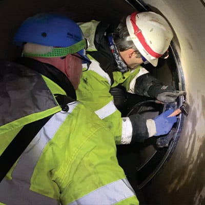 Two HydraTech technicians inserting a wedge into the restraining bands to hold the HydraTite Seal in Place
