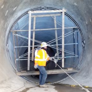 Field Technician Inspecting a seal in a 13ft-Diameter Concrete Pipe