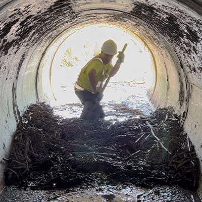 A field technician digging out biomass in a pipe
