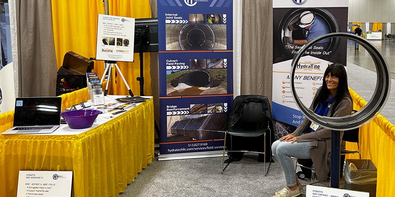 Jennifer sitting at HydraTech's booth at OTEC, framed by the HydraTite Internal Pipe Joint Seal
