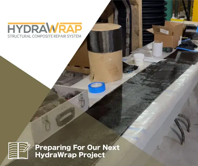 A table cluttered with materials related to HydraWrap, 'Preparing For Our Next HydraWrap Project'