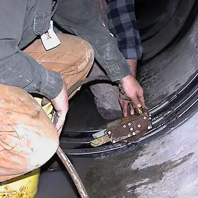 Two technicians installing HydraTite in a round pipe