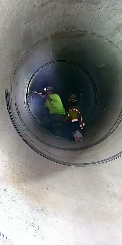 Two technicians installing HydraTite in a round pipe