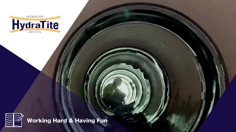 A technician sitting in a pipe that has had HydraTite installed over a joint, 'Working Hard & Having Fun'