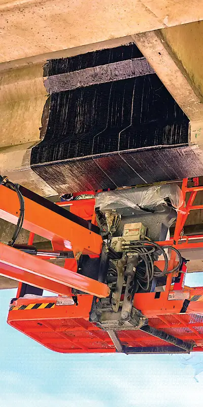 Fiber-wrap-being-applied-to-a-bridges-support-using-a-lift-for-access Two HydraTite Installers