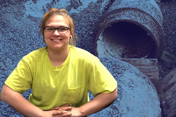 A woman sitting in front of a pipe opening