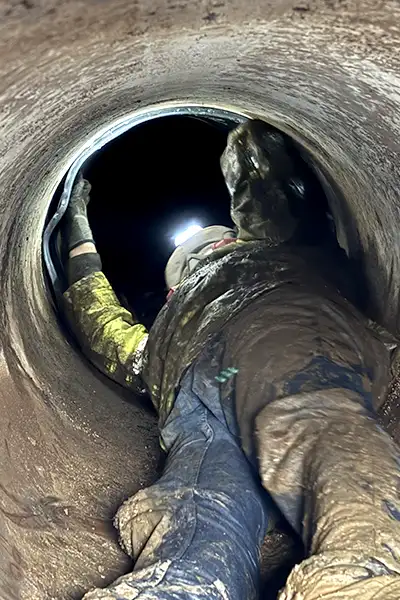 A technician in a small-diameter pipe installing HydraTite, the internal pipe joint seal, over a joint to fortify it against leaks