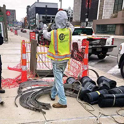 A technician standing near a pipe entry point surrounded by HydraTite materials on the ground